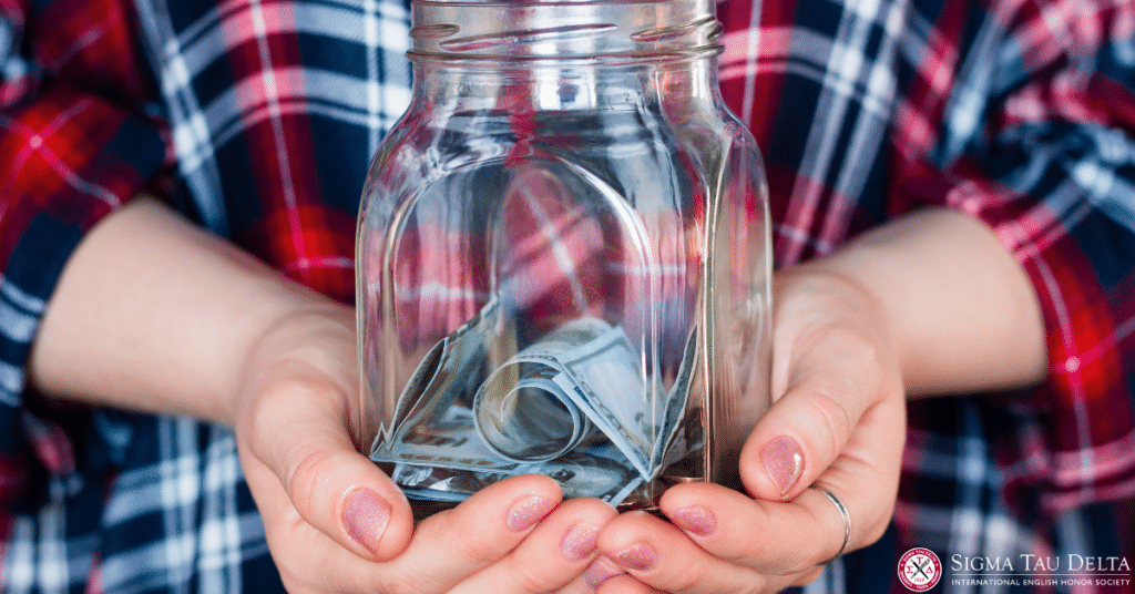 Person wearing red plaid flannel shirt holding glass jar containg folded bills